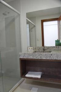 a bathroom with a shower and a sink and a mirror at Hotel Queijo & Cia in Capão Alto