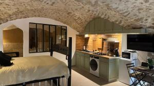 a kitchen with a bed and a kitchen with a sink at Les Voûtes Secrètes - Love Room avec Balnéo à Bras in Bras