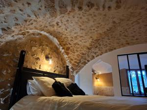 a bedroom with a bed and a stone wall at Les Voûtes Secrètes - Love Room avec Balnéo à Bras in Bras
