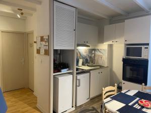 a small kitchen with white cabinets and a table and a table and a table at La Cascade appartement F2 in Eaux-Bonnes