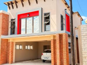 a house with red doors and a car parked in front at Dunamis Lodge in Giyani