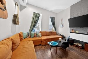 an orange couch in a living room with a guitar at Stylish STL Gem ABODEbucks in Saint Louis
