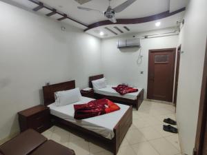a room with two beds in a room with a door at Al Hidayah Hotel Multan in Multan