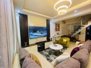 a living room with a large couch and a television at Blue Bell Suites in Lekki