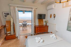 a bedroom with a bed and a balcony with a table at Villa Art Natalie two in Kithnos