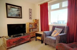 a living room with a tv and a chair at Self-catering Lighthouse Keeper's Cottage on the NC500 in Wick