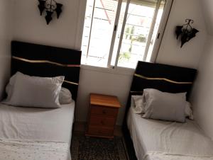 two beds in a small room with a window at Dar Yasmine 2 in Ifrane +3 photos
