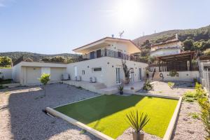 a house with a yard with a green lawn at Villa Keyd Mare in Porto Rafti
