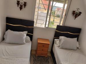 two beds in a small room with a window at Dar Yasmine 2 in Ifrane