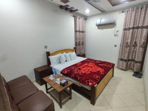 a bedroom with a bed and a couch and a table at Al Hidayah Hotel Multan in Multan +25 photos