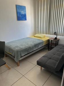 a bedroom with a bed and a couch and a window at casa la luz Orotina in Orotina