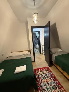 a bedroom with two beds and a door with a rug at WoodCottage in Borjomi