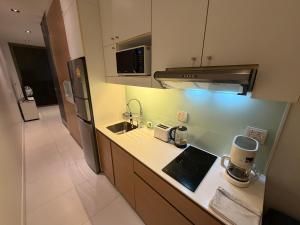 a small kitchen with a sink and a microwave at Modus Pattaya Beachfront Apartment in North Pattaya