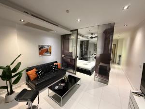 a living room with a black couch and a bedroom at Modus Pattaya Beachfront Apartment in North Pattaya