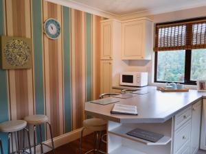 a kitchen with a counter and stools in it at Rosecraddoc Manor - Lakeview in Saint Cleer