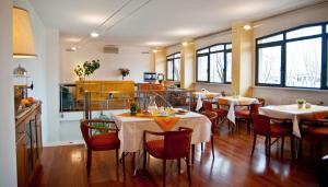un ristorante con due tavoli, sedie e finestre di Hotel Boston a Livorno