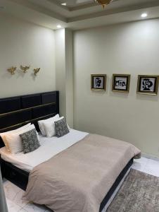 a bedroom with a large bed with three pictures on the wall at Riverhills Comfort 2BHK in Rawalpindi