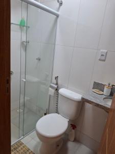 a bathroom with a toilet and a glass shower at Casa na praia prática aconchegante in Serra