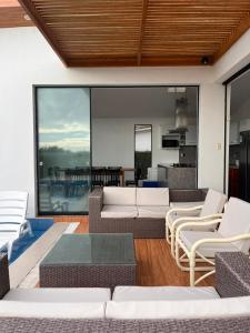 a living room with white furniture and a large window at Casa VerdeMar Vichayito Perú in Vichayito