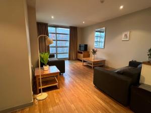a living room with a black couch and a tv at Comfy 2bed flat next to Motorpoint Arena in Nottingham