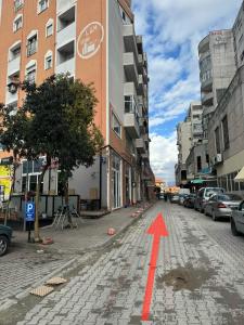 a red arrow on a city street with buildings at Terminal Comfort Apartament in Tirana +2 photos