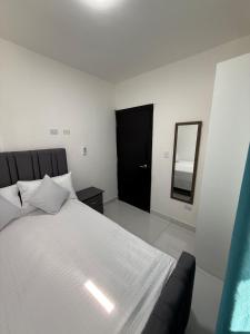 a bedroom with a large white bed and a mirror at Moon Apartamentos D3 in San Cristóbal