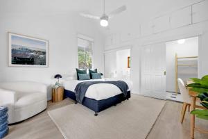 a white bedroom with a bed and a couch at 4 Bed Queenslander City Views Walk to Suncorp Deck + Parking in Brisbane