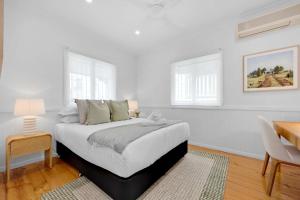 a white bedroom with a bed and a table and chairs at 4 Bed Queenslander City Views Walk to Suncorp Deck + Parking in Brisbane +18 photos