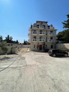 a car parked in front of a large building at The White Troy in Sarandë