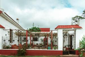 a white building with a fence with tables and chairs at Posada San José de Lucas in Tupambaé
