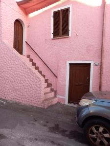 a pink building with stairs and a door at Casa Roberta in Martis +10 photos