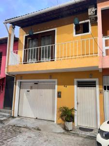 a yellow house with two garage doors and a balcony at Casa Dourada PIPA RN - Sobrado 2 quartos in Pipa