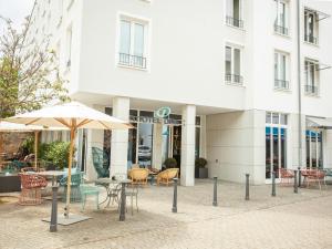 a table and chairs and an umbrella in front of a building at Motel One Saarbrücken in Saarbrücken