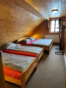 a room with three beds in a wooden cabin at Sauna Chata BedRich in Bedřichov