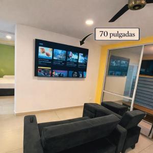 a living room with a couch and a tv on a wall at Cerca al centro, piscinas & jacuzzis y muy dotado in Villeta