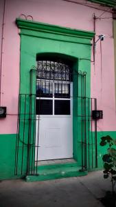 a green and white door in a pink building at The Mercedes Room in Oaxaca City