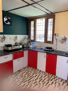 a kitchen with red and white cabinets and windows at Nagwal Hotel in Dharamshala