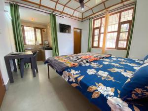 a bedroom with a bed and a table and windows at Nagwal Hotel in Dharamshala