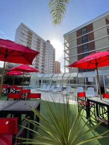 eine Gruppe von Tischen und Stühlen mit roten Sonnenschirmen in der Unterkunft Hotel Chiavari in San Bernardo