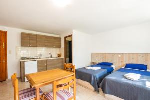 two beds in a room with a table and a kitchen at Barbarossa Apartments in Vrachonisída Prasonísi