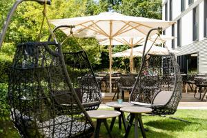 two swing chairs and an umbrella in a yard at Motel One München-Deutsches Museum in Munich
