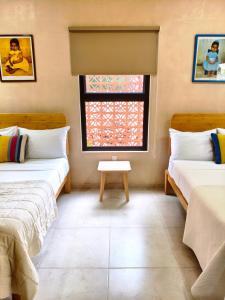 a room with two beds and a window at Villa Lara Palacios, tu oasis en Mérida in Mérida