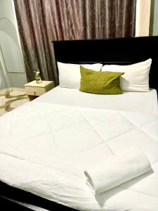 a white bed with white sheets and green pillows at Serenity homes Uganda in Mbale