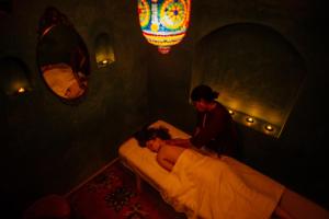 a man helping a woman make a bed in a room at Riad Persephone in Marrakesh