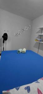 a bedroom with a blue bed with shoes on it at Pousada Familiar 04 in Rio do Sul