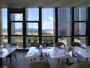 a dining room with tables and chairs and a large window at Novotel Deqing Moganshan in Deqing