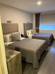 a hotel room with two beds and a window at HUNICO HOTEL in Tulancingo