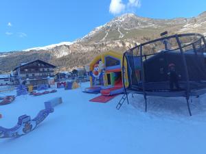 a playground in the snow in front of a mountain at Alexander Lodge in Isolaccia