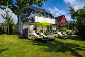 a group of chairs and an umbrella in front of a house at FH Luisenlund im Ostseebad Prerow in Prerow