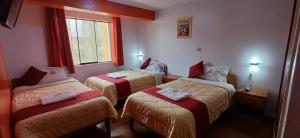 a hotel room with three beds and a window at Krusty Hostel B&B in Huaraz